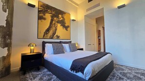 A bedroom with a large bed, bedside lamps, a wall-mounted artwork, and a wardrobe. - Designer Apartment in Rosebery (Rosebery)