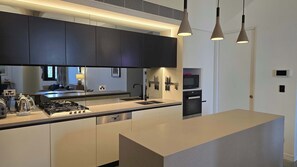 A modern kitchen with a central island, built-in appliances, and pendant lighting. - Designer Apartment in Rosebery (Rosebery)