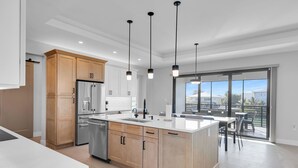 A modern kitchen with a central island, stainless steel appliances, and a view to the outside. - Coco Plum Palms New Waterfront Pool Spa Dock (Marathon)