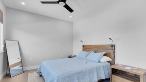A bedroom with a bed, bedside table, nightstand, and a ceiling fan. - Coco Plum Palms New Waterfront Pool Spa Dock (Marathon)