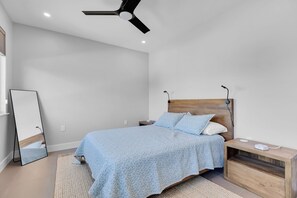 Ein Schlafzimmer mit Bett, Nachttisch und Deckenventilator.