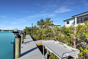 Eine Anlegestelle mit Booten, ein weißes Gebäude mit Balkon und üppiges Grün.