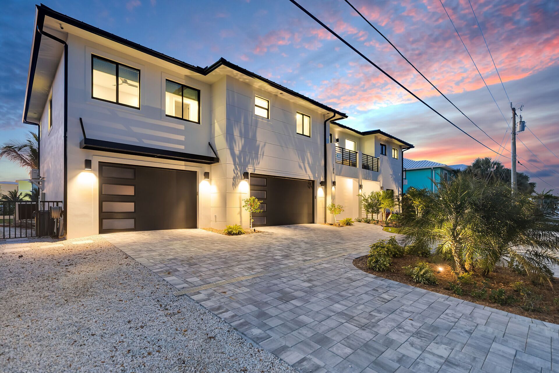 A modern two-story house with a driveway, garage doors, and a landscaped garden.