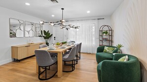 Ein moderner Essbereich mit einem Holztisch, grauen Stühlen und einem grünen Sofa.