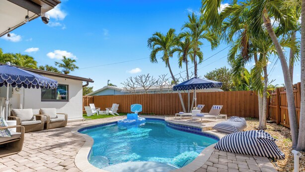 Ein Garten mit Swimmingpool, Liegestühlen und Palmen.