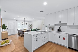 A modern kitchen with white cabinetry, a central island, and a stainless steel dishwasher. - Quiet Oasis-Heated Pool •Fire Pit •Outdoor Games (Fort Lauderdale)