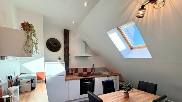 A compact kitchen with a dining area, a clock, and a skylight. - Charm & Tranquility in the Heart of Troyes (Troyes)