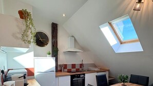 A modern kitchen with a dining area, a clock, and a skylight. - Charm & Tranquility in the Heart of Troyes (Troyes)