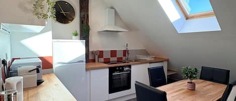 A modern kitchen with a dining area, a clock, and a skylight.