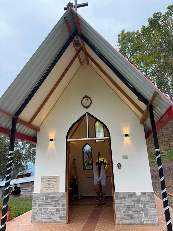 Una iglesia con techo a dos aguas, campanario y vidriera.
