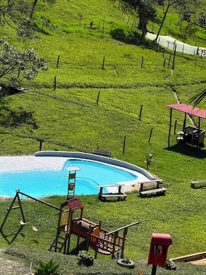 Un patio trasero residencial con piscina, un muelle de madera y un buzón rojo.