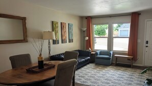 A living room with a dining table, chairs, sofas, and a patterned rug. - The Briargate Bungalow only 5 Mins to USAFA with Pikes Peak Views (Colorado Springs)