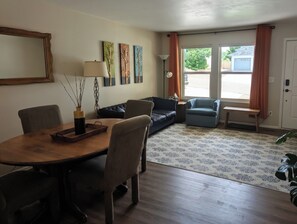 A living room with a dining table, chairs, sofas, and a patterned rug. - The Briargate Bungalow only 5 Mins to USAFA with Pikes Peak Views (Colorado Springs)