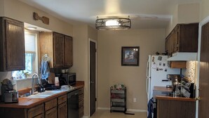 A kitchen with wooden cabinets, a refrigerator, a coffee maker, and a microwave. - The Briargate Bungalow only 5 Mins to USAFA with Pikes Peak Views (Colorado Springs)