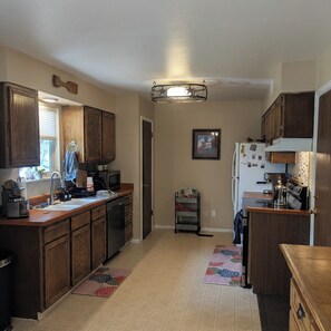 A kitchen with wooden cabinets, a refrigerator, a coffee maker, and a microwave. - The Briargate Bungalow only 5 Mins to USAFA with Pikes Peak Views (Colorado Springs)