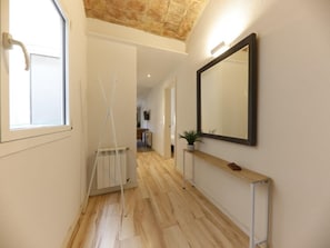Ein Flur mit Holzboden, Heizkörper, einer weißen Tür und einem großen Spiegel an der Wand.