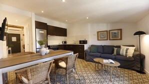 Uma sala de estar moderna com um sofá, uma mesa de jantar com cadeiras e uma área de cozinha.