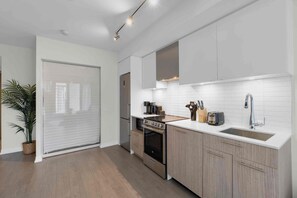 A modern kitchen with a built-in oven, a sink, and a countertop with various appliances. - City Center – Walkable 2BR, 5 min to Eaton Centre (Toronto)