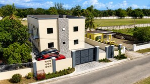 Ein modernes, zweistöckiges Gebäude mit Garage, umgeben von Grünflächen und blauem Himmel.
