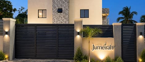 A modern building with a gated entrance, a stone facade, and a sign that reads 'Jumeirah.'