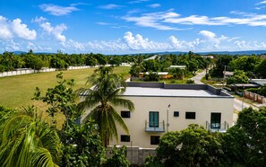 A modern building with a flat roof, surrounded by lush greenery and a clear sky.
