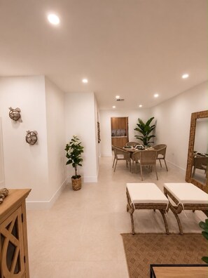 Ein modernes Interieur mit Essbereich, zwei Lounge-Sesseln, einem großen Spiegel und Wanddekoration.