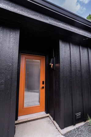 A black exterior with a brown door and a small step leading to the entrance.