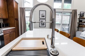 A kitchen with a built-in sink, wooden countertop, and a stainless steel faucet.