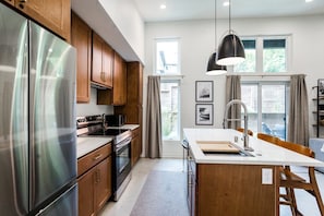 A modern kitchen with stainless steel appliances, wooden cabinets, and a central island with a sink.