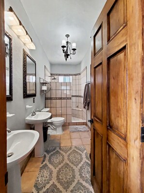 A bathroom with a wooden door, a chandelier, a toilet, a sink, and a mirror. - Beautiful Apartment with amazing views ! A hidden gem! (San José del Cabo)