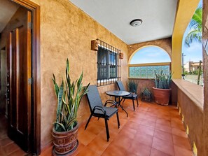 A balcony with a tiled floor, a table, two chairs, and potted plants. - Beautiful Apartment with amazing views ! A hidden gem! (San José del Cabo)