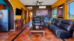 A living room with a black leather sofa, a wooden coffee table, and a television on the left wall. - Beautiful Apartment with amazing views ! A hidden gem! (San José del Cabo)