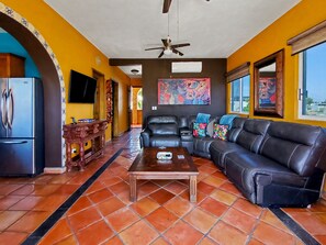A living room with a black leather sofa, a wooden coffee table, and a television on the left wall. - Beautiful Apartment with amazing views ! A hidden gem! (San José del Cabo)