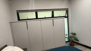Makuuhuone, jossa on sänky, vaatekaappi ja ruukussa oleva kasvi.