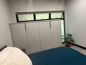 Ein Schlafzimmer mit einem Bett, einem Kleiderschrank und einer Topfpflanze.