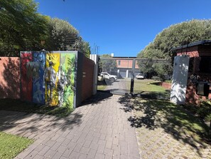 Ein verschlossenes Tor mit Wandgemälde, ein Backsteinhaus und ein umzäunter Garten.