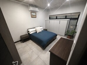 A bedroom with a bed, bedside tables, a wardrobe, and a desk.