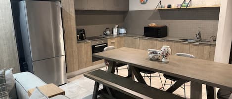A modern kitchen with a built-in refrigerator, a dining table with benches, and a microwave.