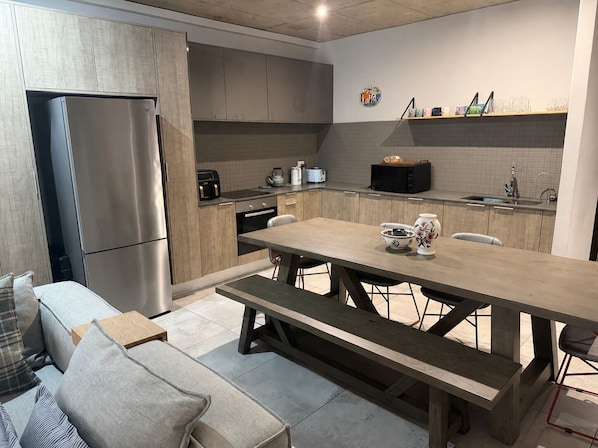A modern kitchen with a built-in refrigerator, a dining table with benches, and a microwave.