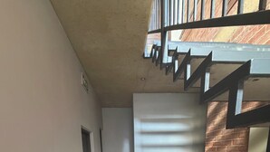Käytävän lattia on laatoitettu, siinä on metallikaiteilla varustetut portaat ja seinä on tehty tiilistä.