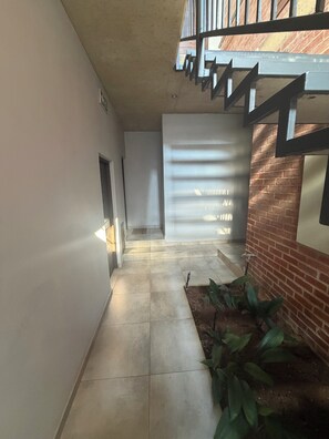 Ein Korridor mit Fliesenboden, einer Treppe mit Metallgeländern und einer Ziegelwand.