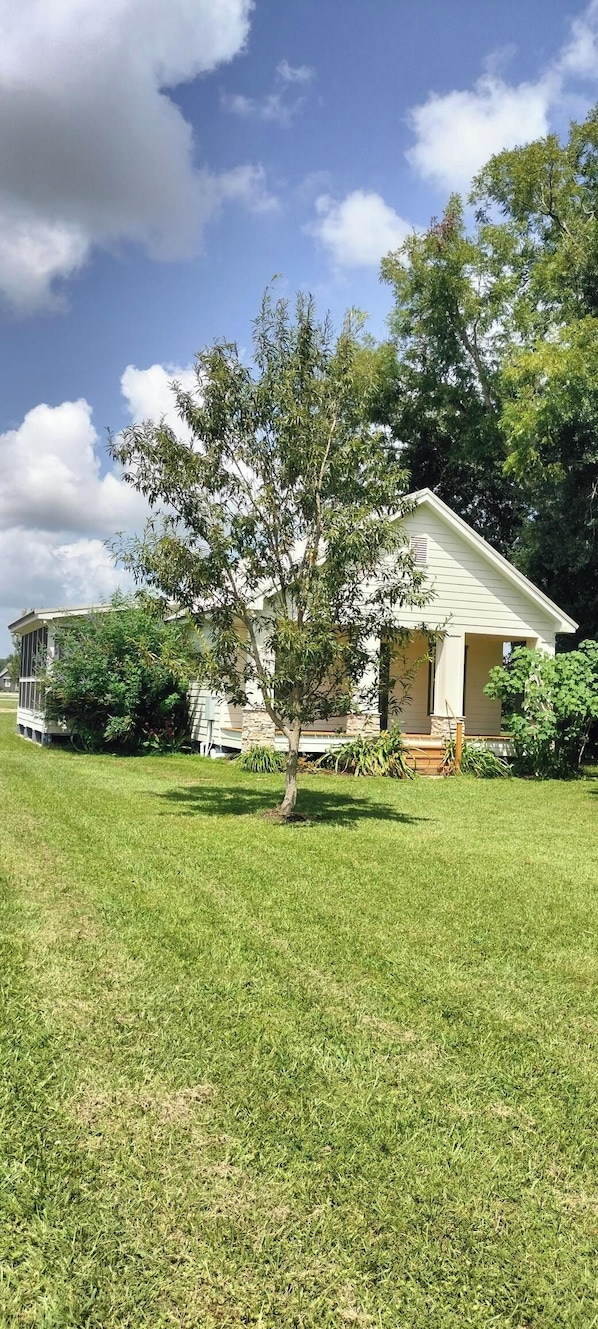A single-story house with a front porch, surrounded by a well-maintained lawn and trees.
