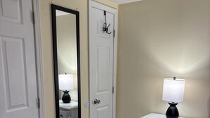 Ein Schlafzimmer mit Bett, Kommode, Spiegel und Tür.