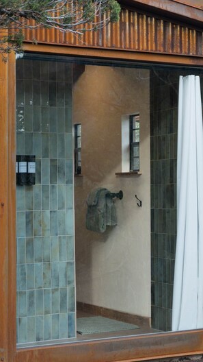 Ein Badezimmer mit Glastür, einem Handtuch an einem Haken und einem kleinen Fenster.