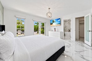 Quarto moderno com cama grande, TV e vista para o exterior.