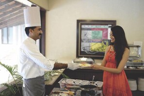 A buffet setup with a server and a guest. - Tropicana Resort and Spa Alibaug (Alibag)