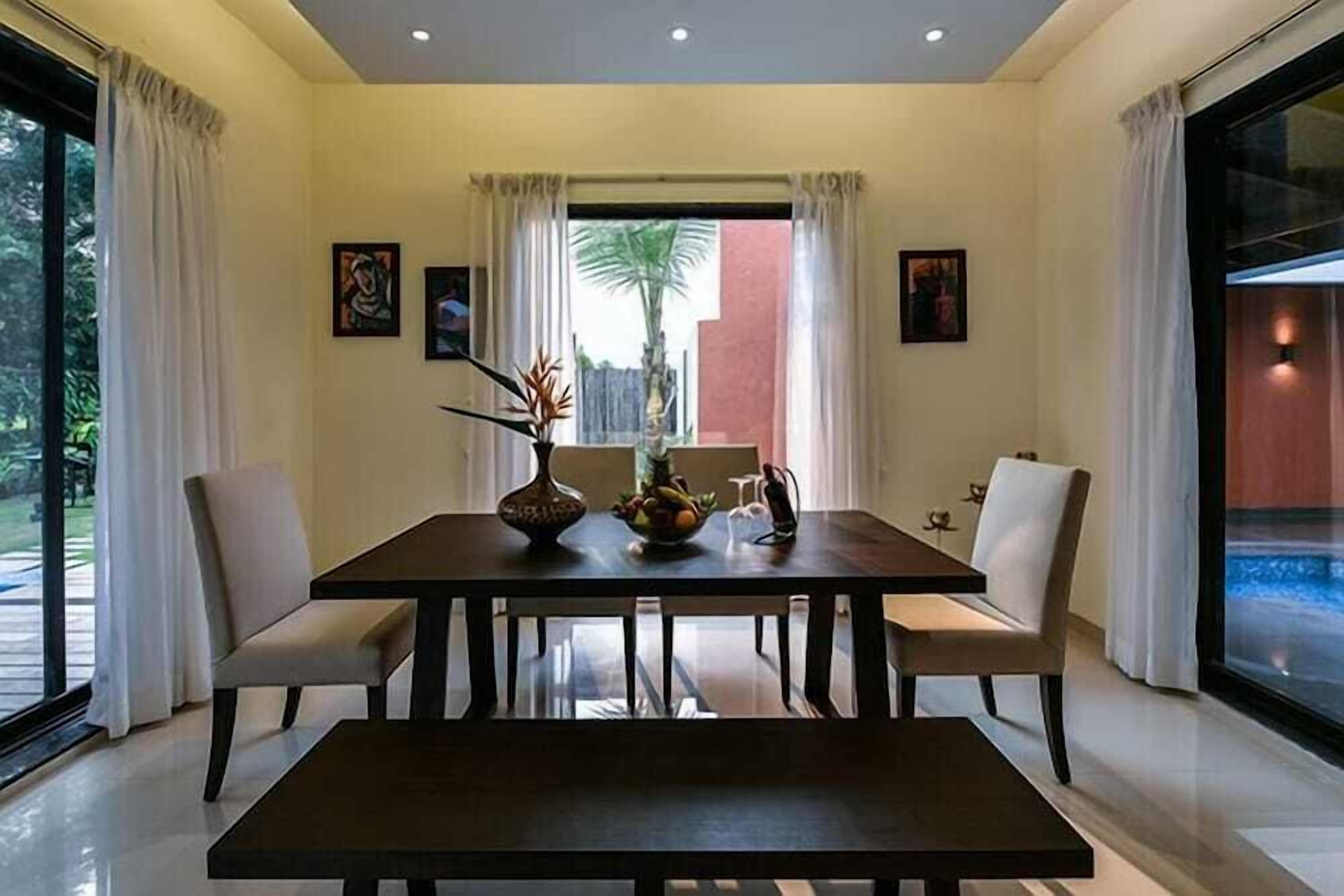 A dining area with a table, chairs, and a vase with flowers.