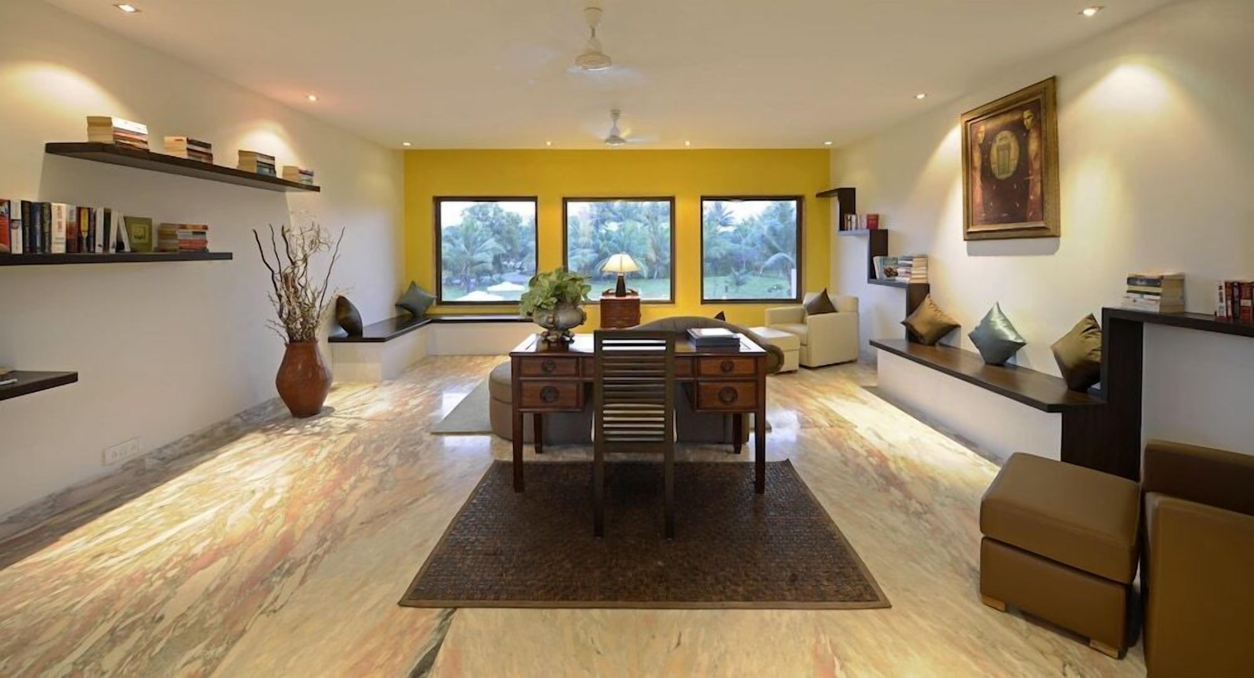 A modern living room with a desk, bookshelves, and a large window.