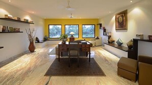 A modern living room with a desk, bookshelves, and a large window. - Tropicana Resort and Spa Alibaug (Alibag)