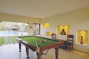 A pool table with balls, a chair, and a decorative item on a wall. - Tropicana Resort and Spa Alibaug (Alibag)